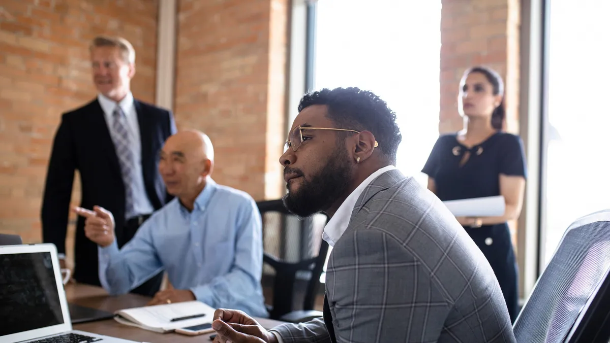 Executives in a brick-walled meeting room turning toward a presentation