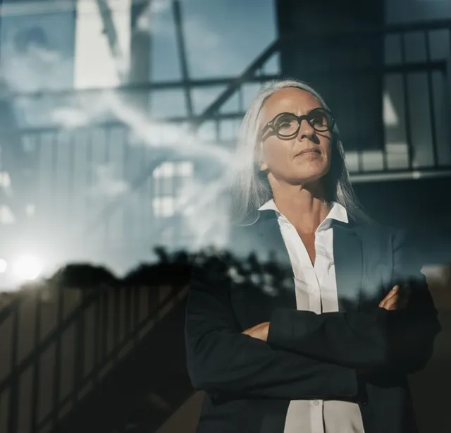 Gray-haired executive with arms crossed outside a glass office building
