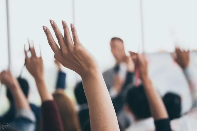 Audience members raising hands during a training session