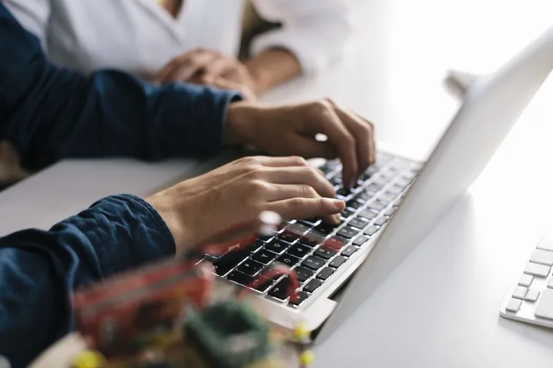 Closeup of hands typing on a laptop keyboard