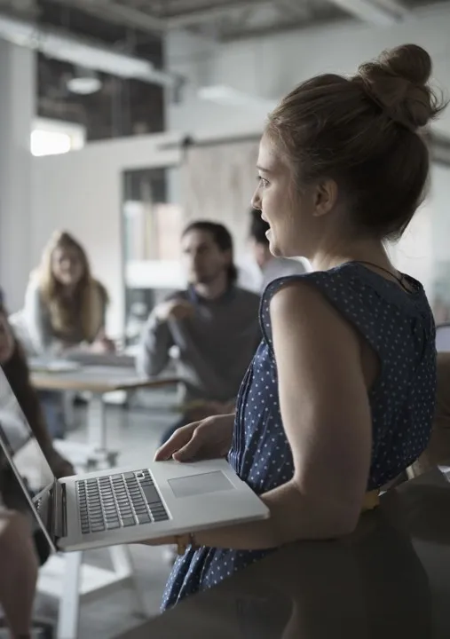 Woman holding a laptop while leading a small group discussion